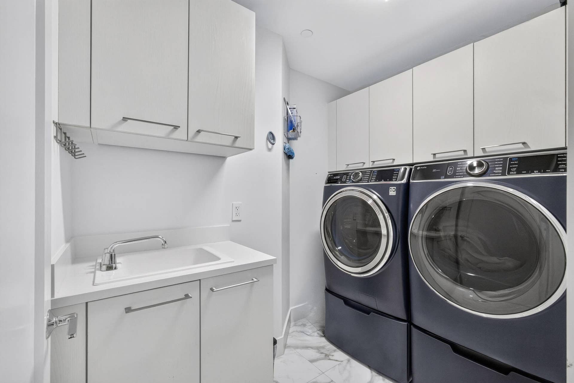 1 Water Club Way, #503, North Palm Beach, FL 33408 Convenient Laundry area with white cabinetry, a utility sink, and stone-finish flooring. Recently purchased upgraded appliances.