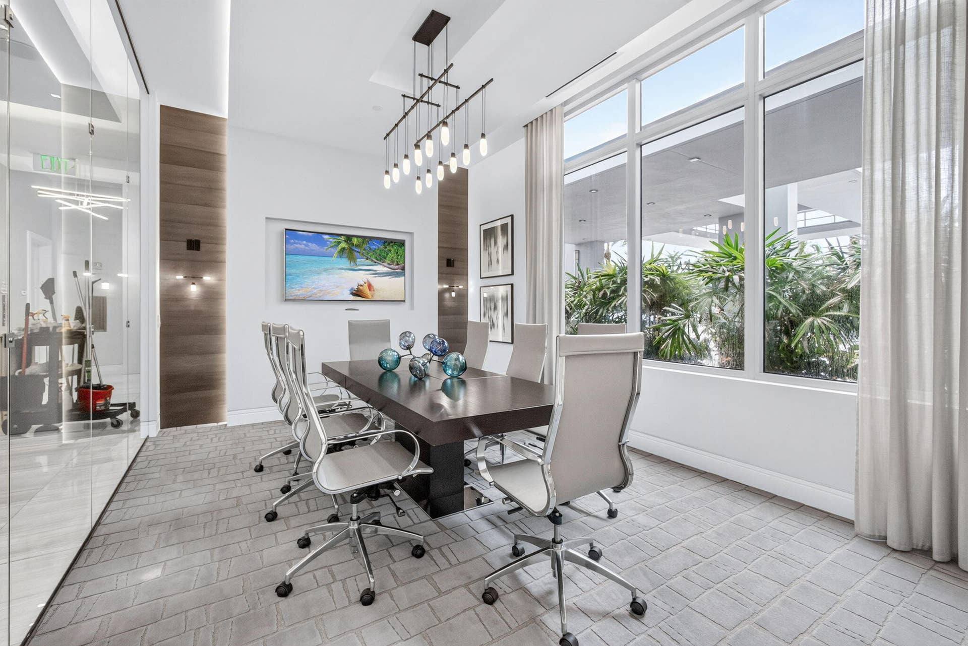 1 Water Club Way, #503, North Palm Beach, FL 33408 Wall-mounted display, full-height glass partition, wood panel accent wall, contemporary linear chandelier, floor-to-ceiling windows with sheer drapery