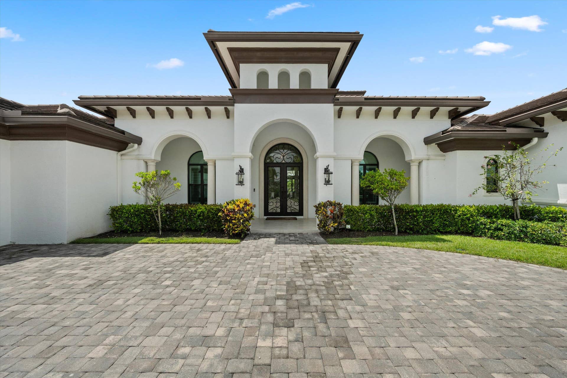 843 STALLION Drive, Loxahatchee, FL 33470 Stucco exterior with arched entryways, a paver driveway, and a central tower element