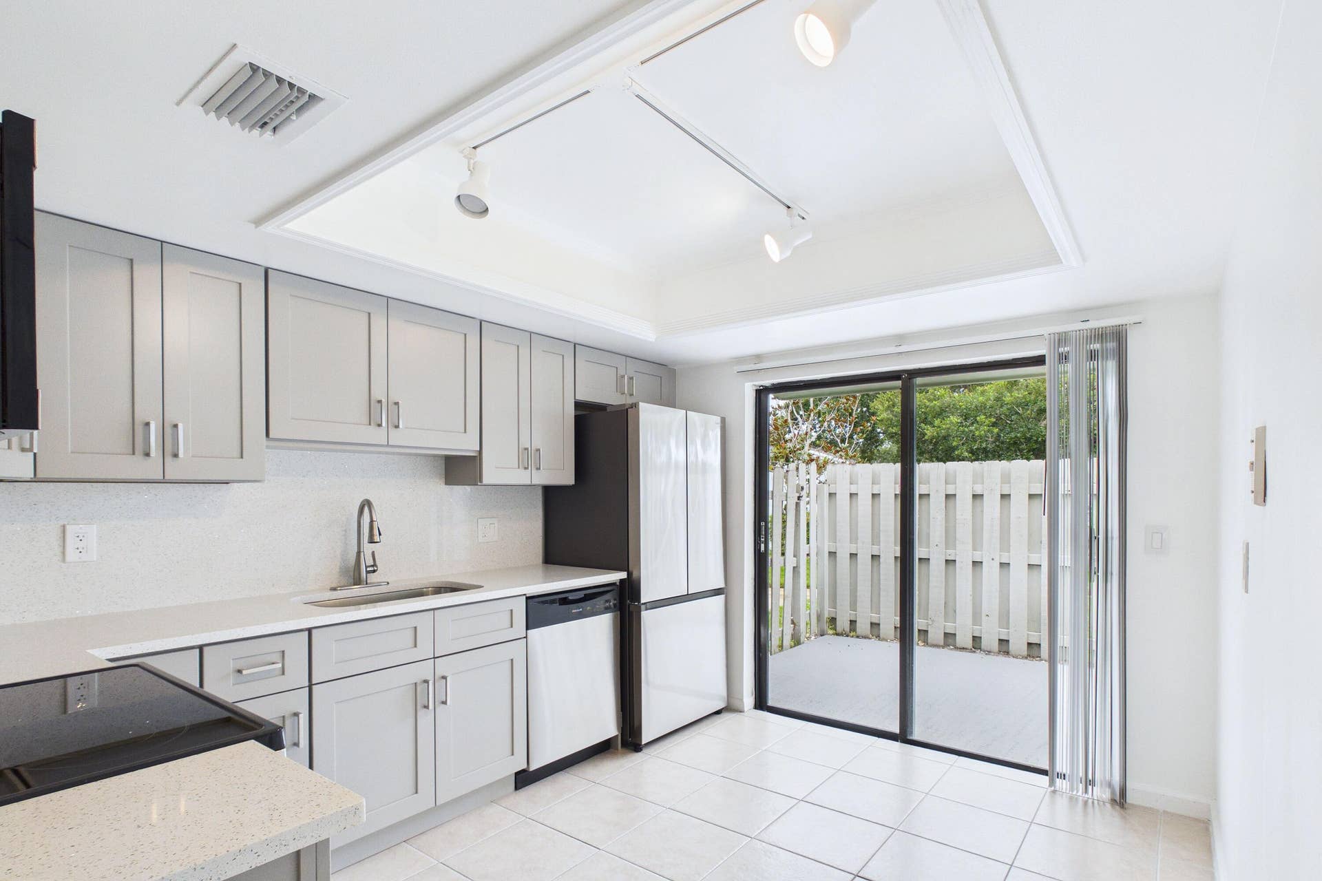 Kitchen with light gray shaker cabinetry, white speckled countertops, a white subway tile backsplash, and a stainless steel sink with a gooseneck faucet