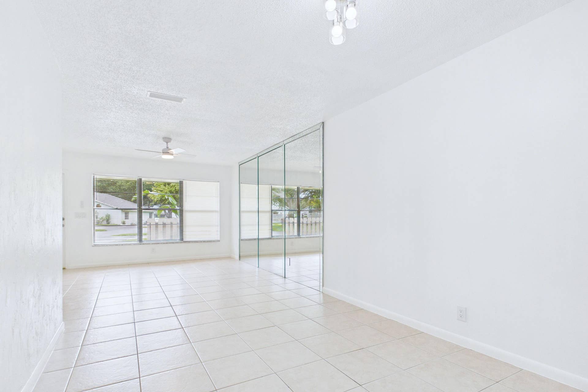 Tile flooring,, ceiling fan with light fixture, window with horizontal blinds, flush mount light fixture