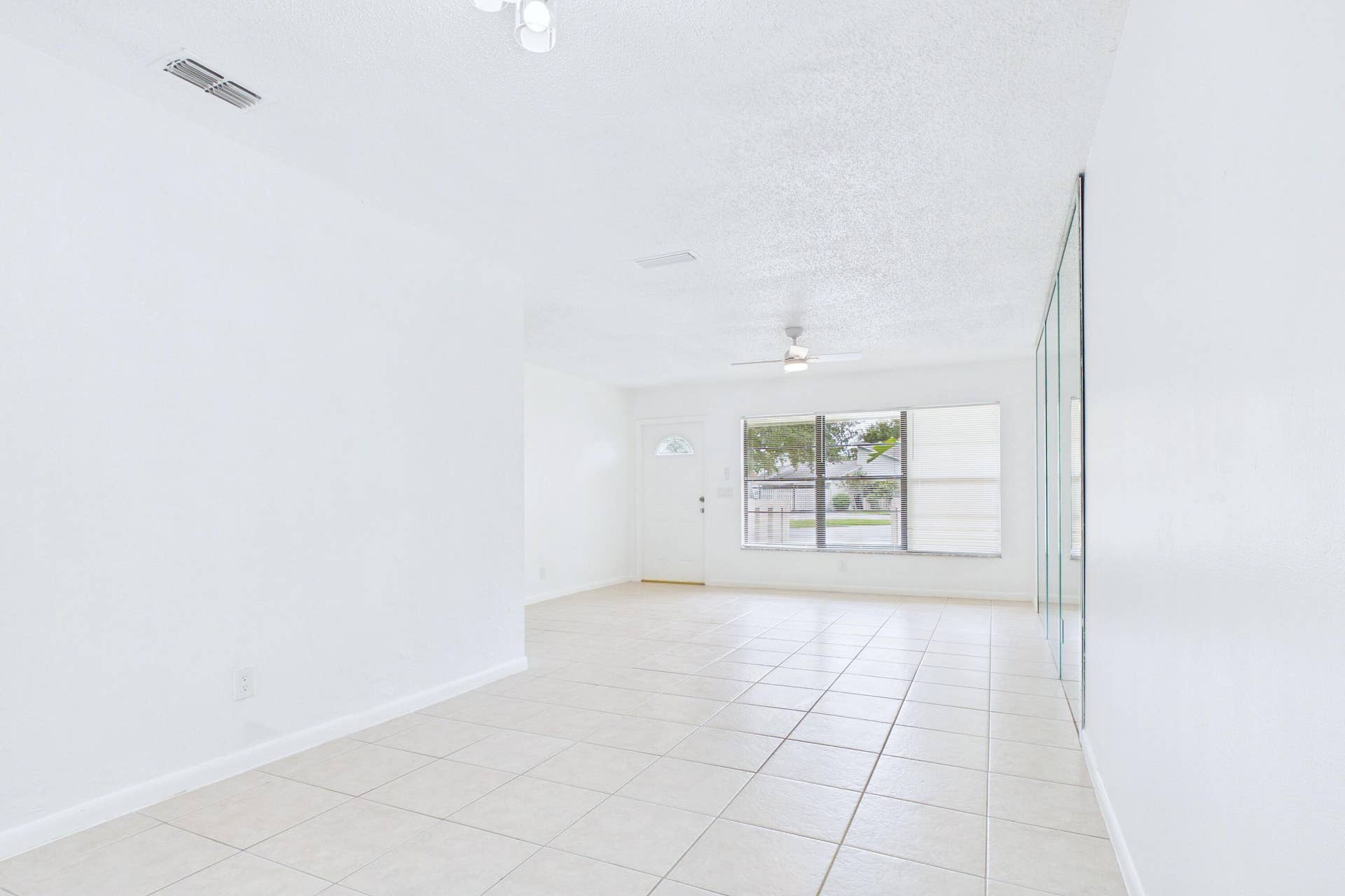 Tile flooring, white walls, ceiling fan, track lighting, mirrored wall panels