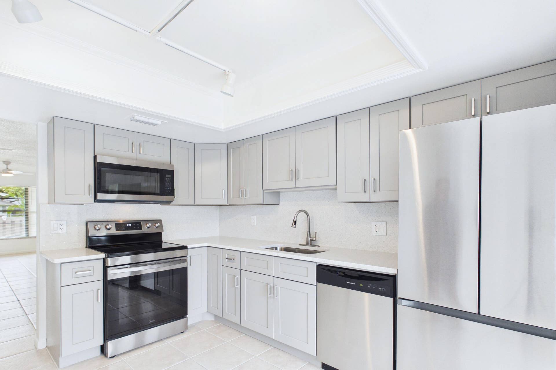 Kitchen featuring light gray cabinetry, stainless steel appliances, white countertops, and tile flooring