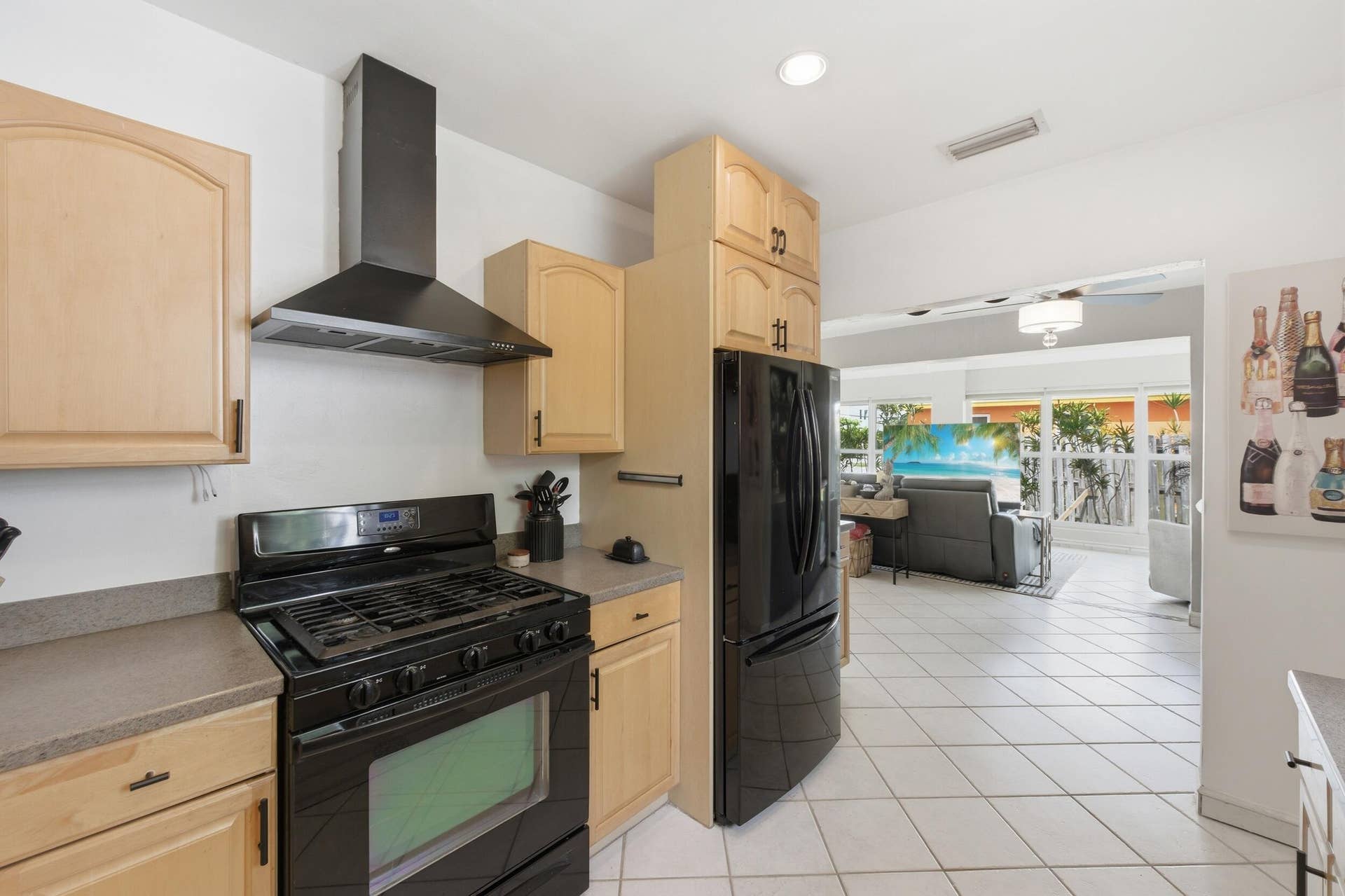 1421 SW 20 Street, Fort Lauderdale, FL 33315 Kitchen featuring light wood cabinetry, black appliances, a range hood, and tile flooring