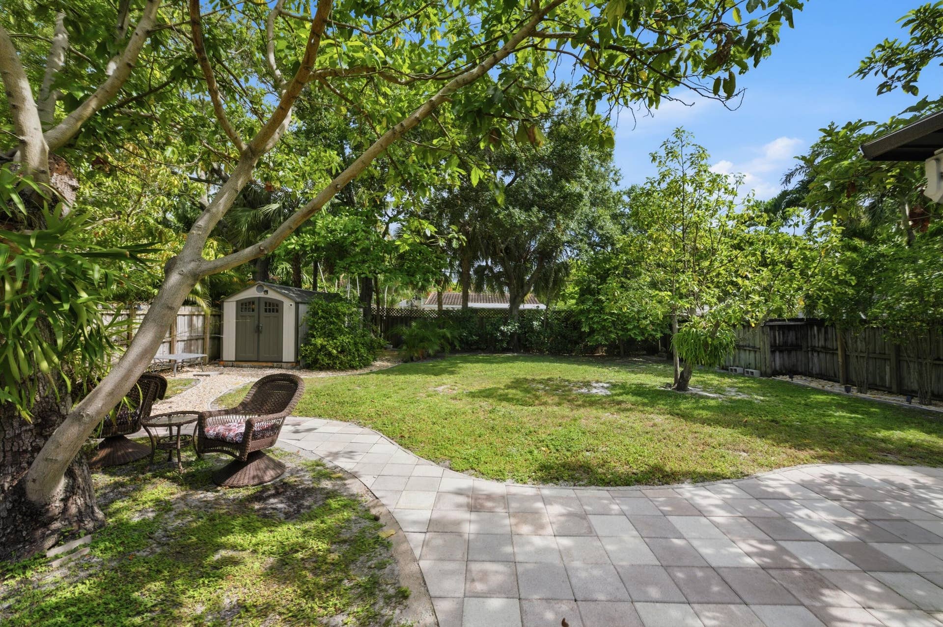 1421 SW 20 Street, Fort Lauderdale, FL 33315 Expansive backyard featuring a paver patio, manicured lawn, mature trees, and a storage shed