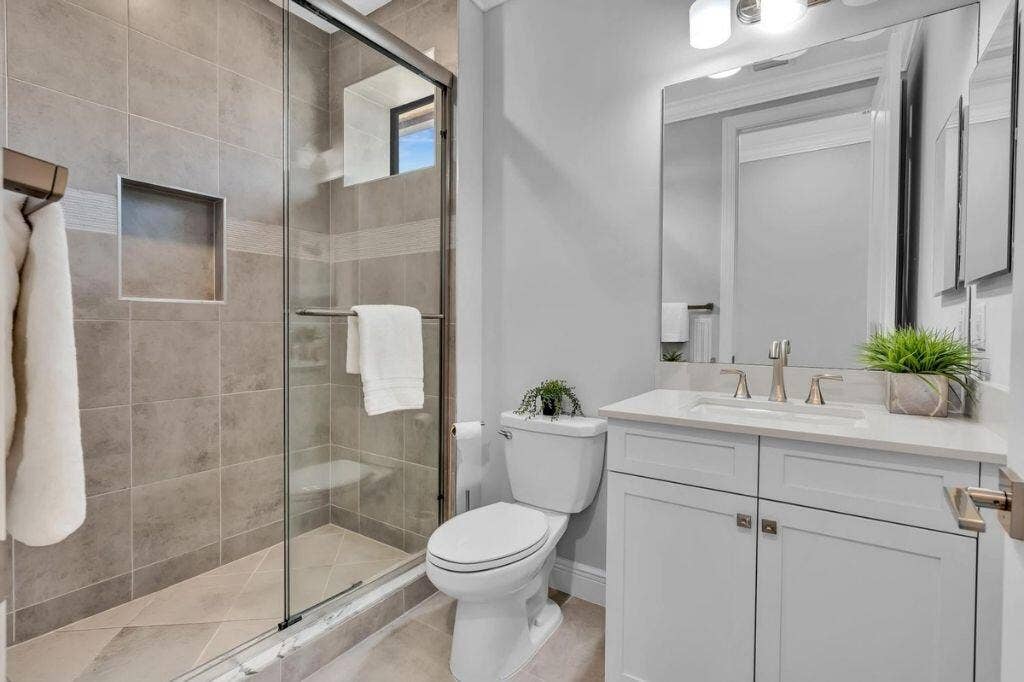 12143 S Baypoint Circle, Parkland, FL 33076 Bathroom featuring a glass-enclosed shower with tile surround and built-in niche