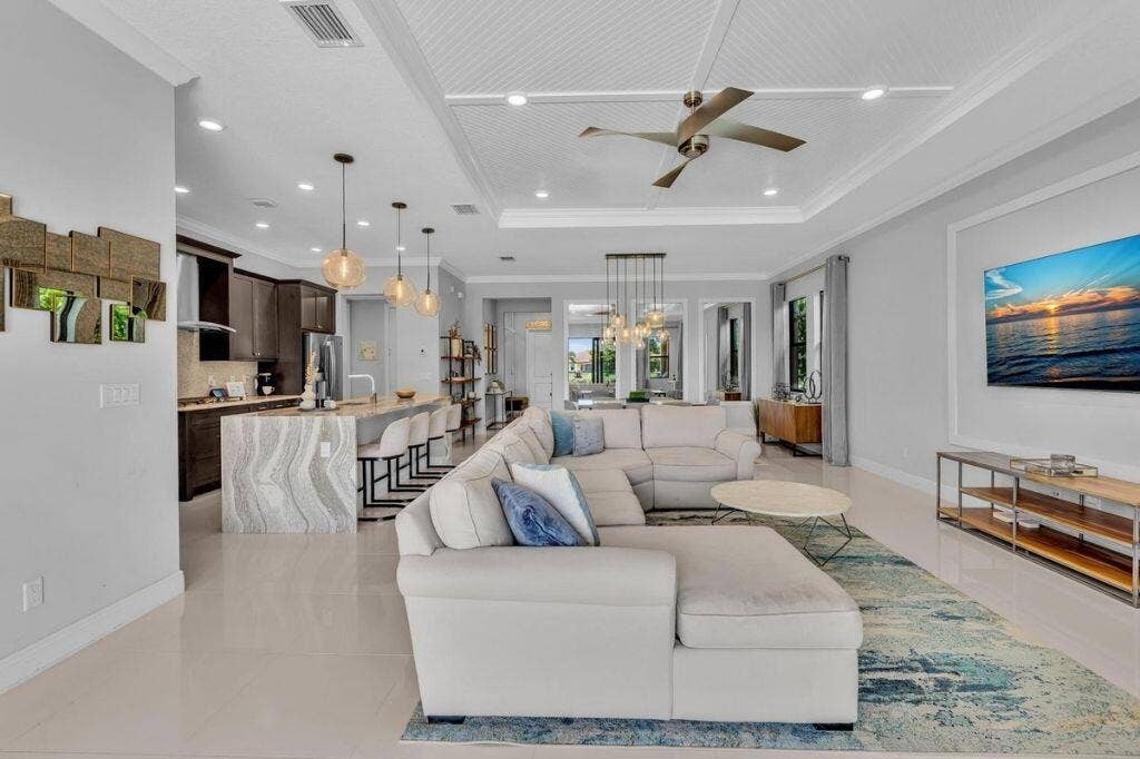 12143 S Baypoint Circle, Parkland, FL 33076 Open-concept living space featuring sleek tile flooring and a tray ceiling with a contemporary ceiling fan
