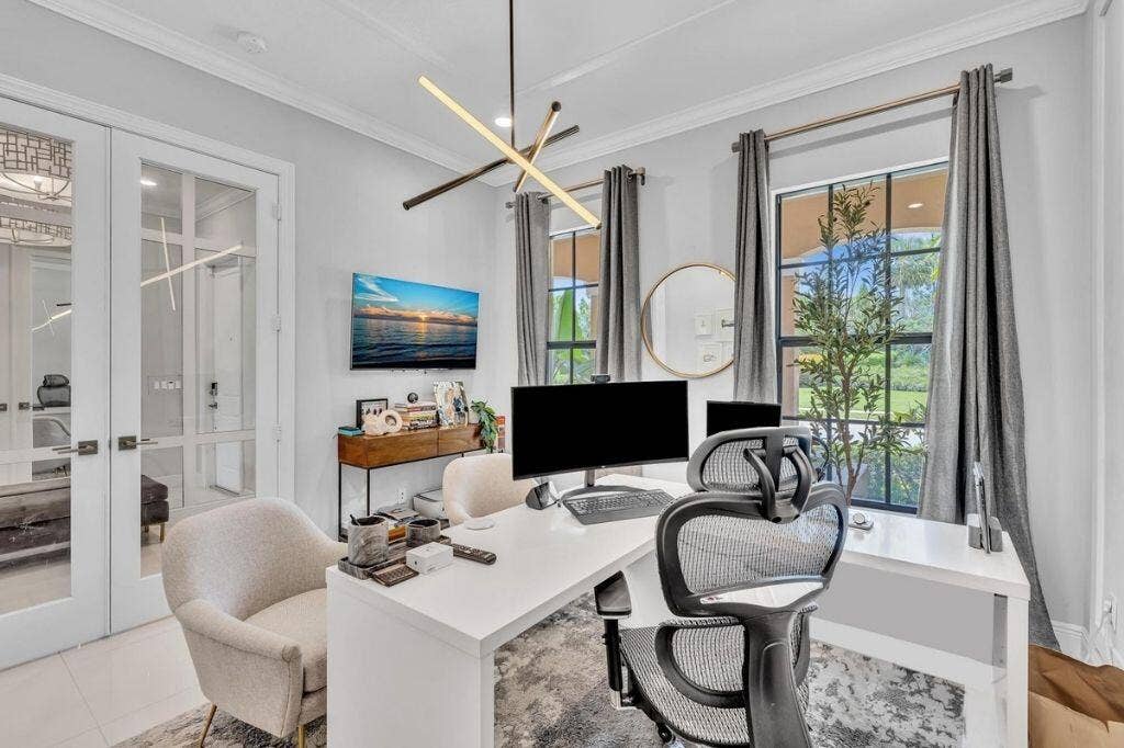 12143 S Baypoint Circle, Parkland, FL 33076 Bright room featuring double French doors with glass panels, a modern linear chandelier, and two large windows with dark frames