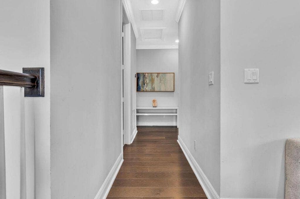 12143 S Baypoint Circle, Parkland, FL 33076 Hallway featuring wood-finish flooring, light gray wall paint, white baseboards, and crown molding