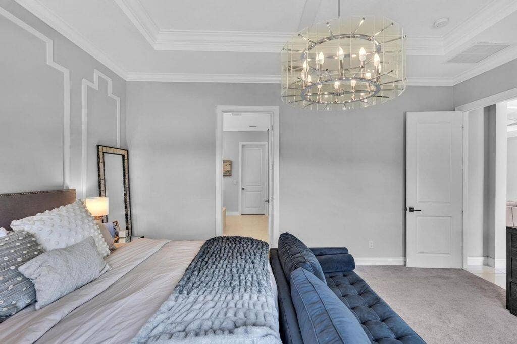 12143 S Baypoint Circle, Parkland, FL 33076 Tray ceiling with crown molding, decorative wall molding, contemporary chandelier, and two-panel interior doors