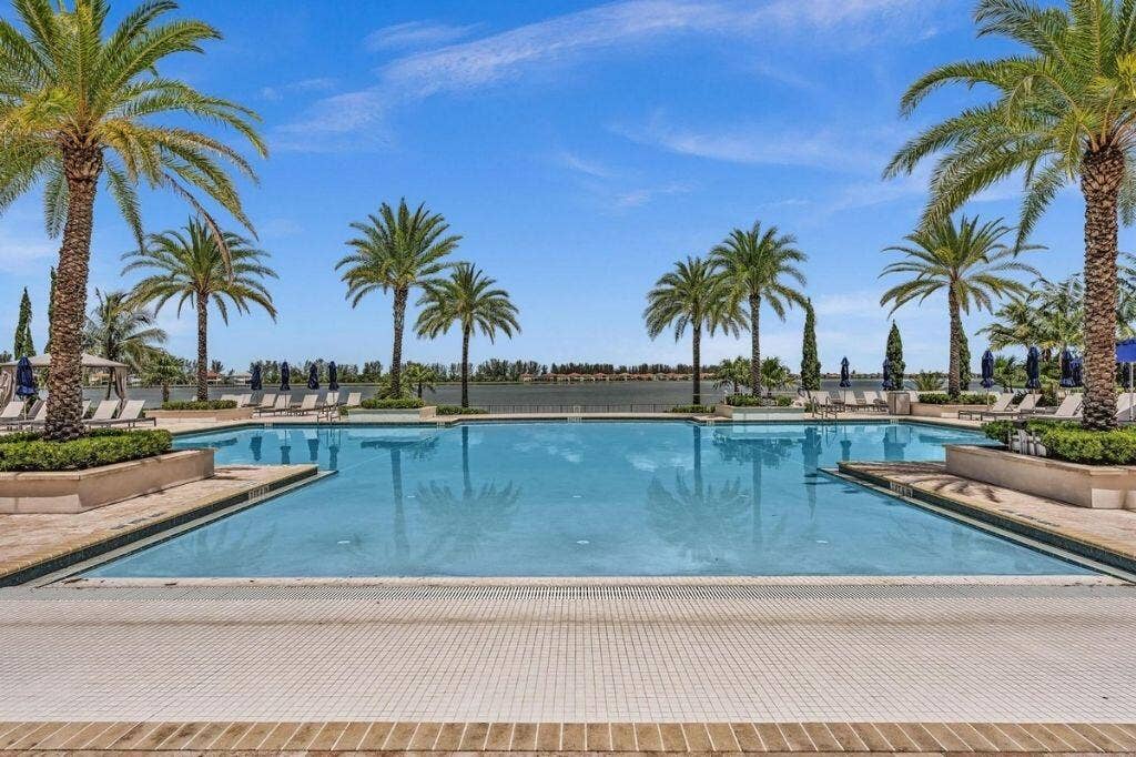12143 S Baypoint Circle, Parkland, FL 33076 Expansive outdoor pool area featuring a large swimming pool with integrated spa, surrounded by mature palm trees and lush landscaping