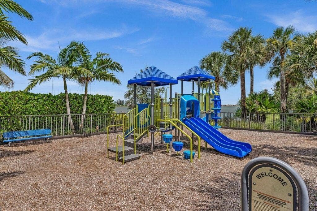 12143 S Baypoint Circle, Parkland, FL 33076 Recreational playground with blue and yellow play structures, a slide, and a bench, set on a wood chip surface