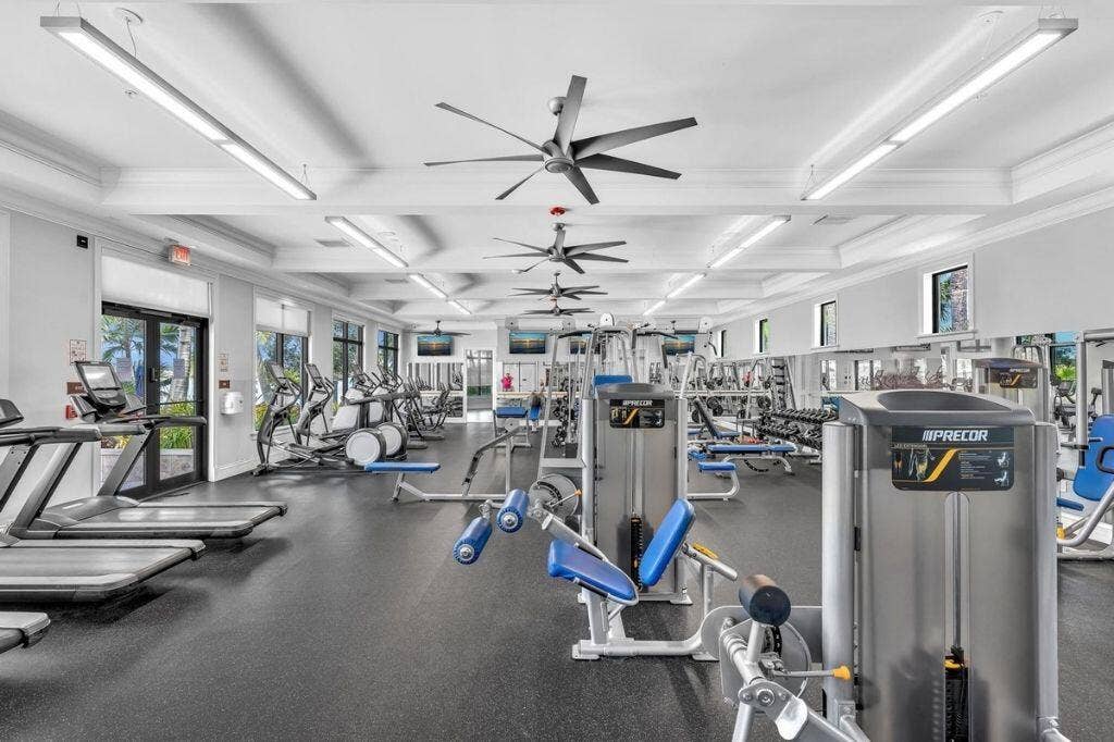 12143 S Baypoint Circle, Parkland, FL 33076 Spacious fitness center featuring various exercise equipment, resilient rubber flooring, overhead lighting, multiple ceiling fans, and large windows