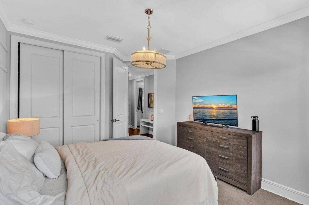 12143 S Baypoint Circle, Parkland, FL 33076 Bedroom featuring a built-in closet with double panel doors, crown molding, a ceiling-mounted drum light fixture, and light gray wall paint
