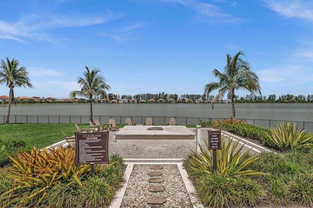 12143 S Baypoint Circle, Parkland, FL 33076 Outdoor communal area featuring a fire pit, Adirondack chairs, and a serene lake backdrop