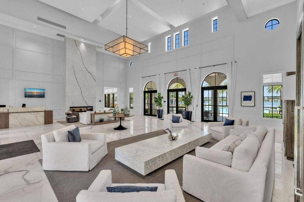 12143 S Baypoint Circle, Parkland, FL 33076 Grand lobby featuring a towering fireplace with large-format veined slab surround, high ceilings with recessed lighting, and expansive arched doorways