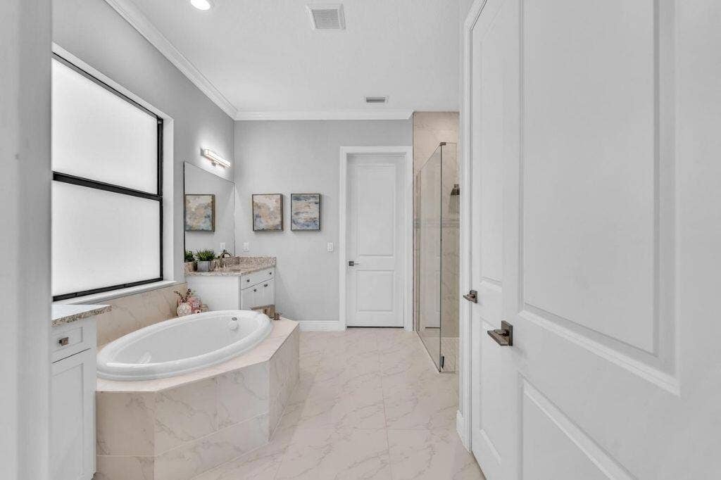 12143 S Baypoint Circle, Parkland, FL 33076 Soaking tub with tiled surround, large window, and light-toned flooring