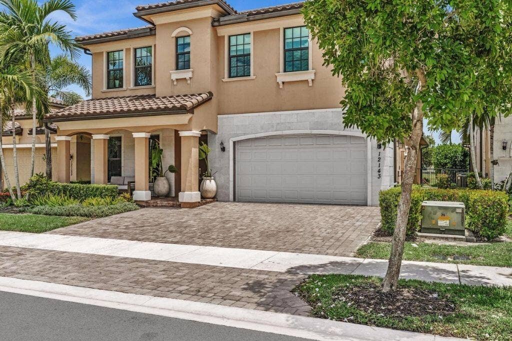 12143 S Baypoint Circle, Parkland, FL 33076 Two-story stucco residence featuring a tile roof and decorative columns at the front entry