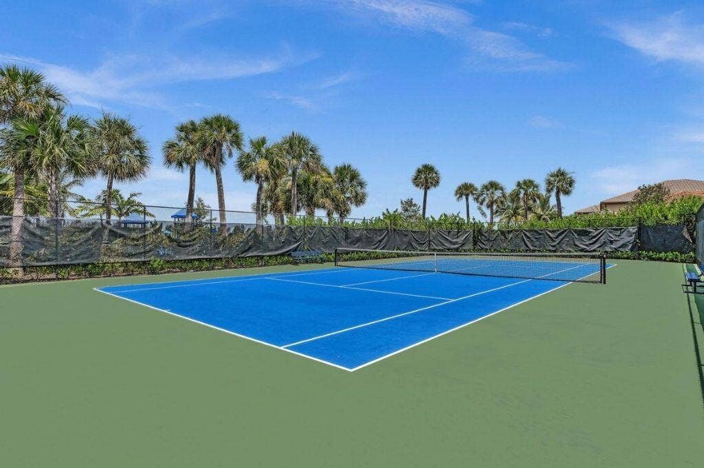 12143 S Baypoint Circle, Parkland, FL 33076 Full-size tennis court featuring a blue playing surface and green surrounding area