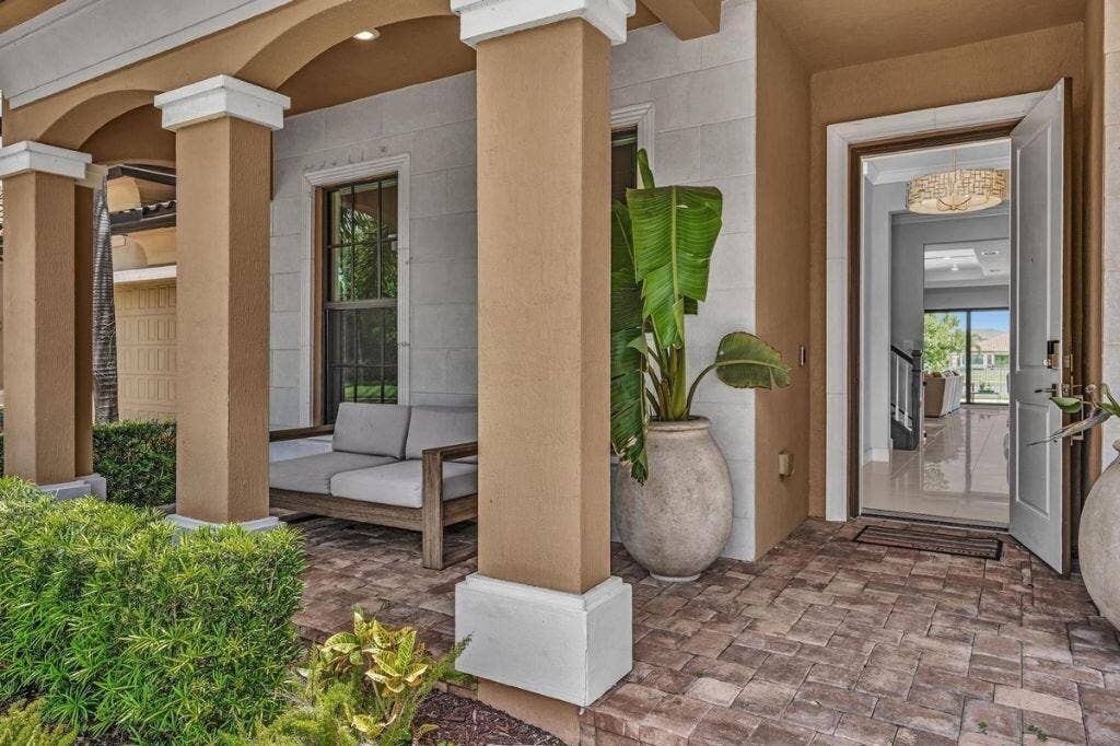 12143 S Baypoint Circle, Parkland, FL 33076 Covered front entry featuring a paver stone patio, decorative columns, and a solid wood front door