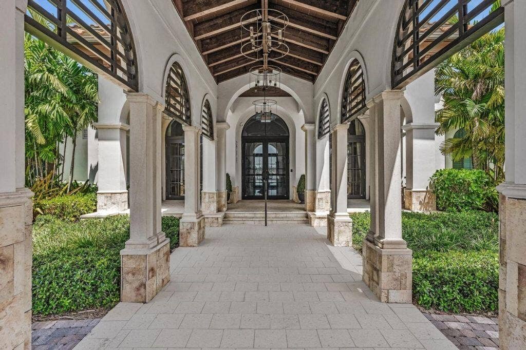 12143 S Baypoint Circle, Parkland, FL 33076 Arched portico entry with natural stone columns, wood ceiling beams, and a grand double-door entrance
