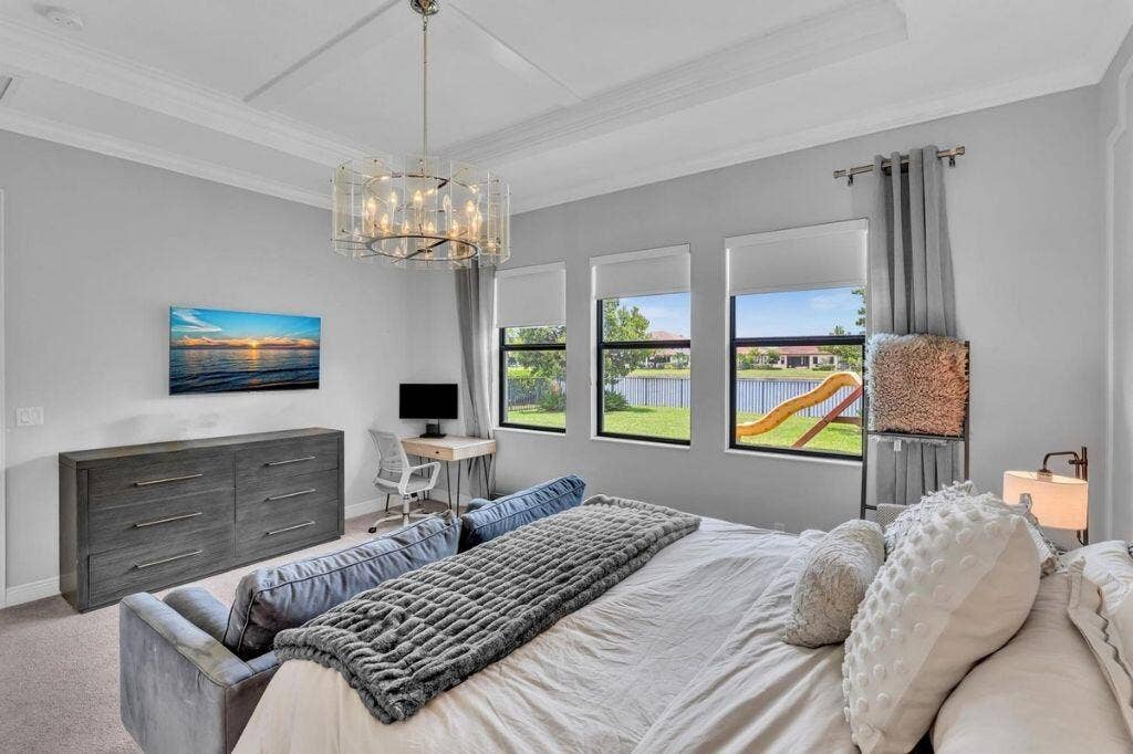 12143 S Baypoint Circle, Parkland, FL 33076 Spacious interior featuring a coffered ceiling with a decorative chandelier, multiple windows with roller shades, and a built-in desk area