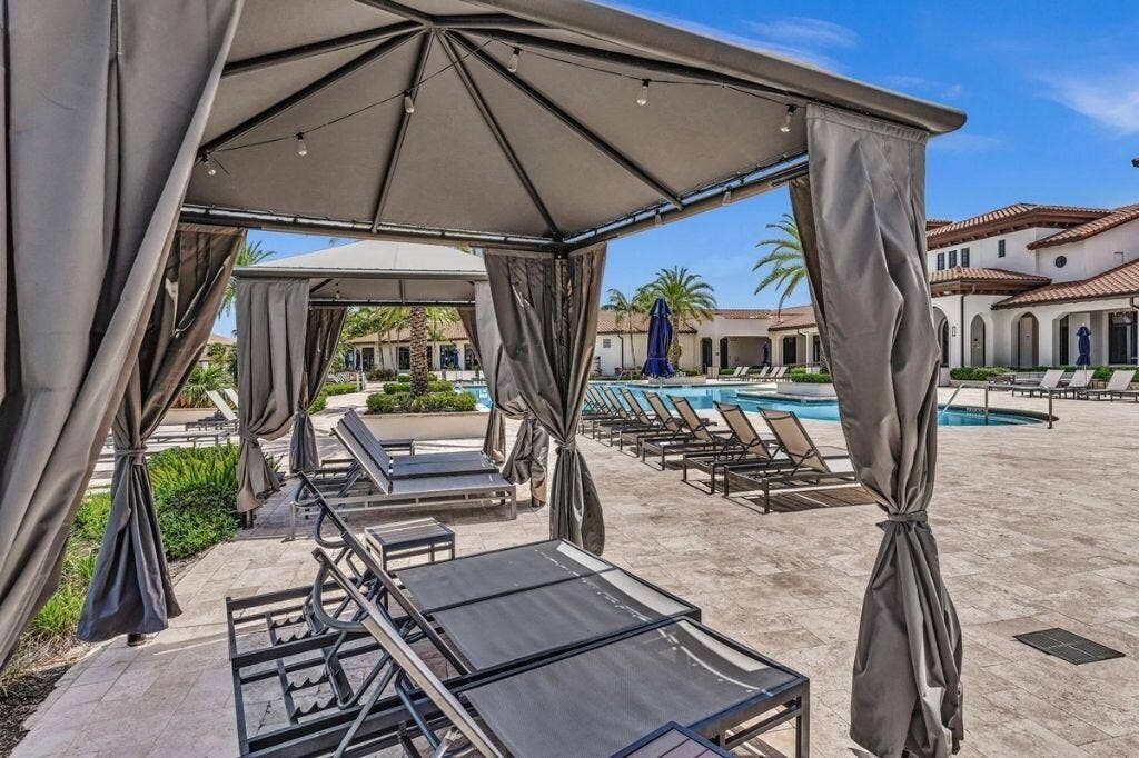 12143 S Baypoint Circle, Parkland, FL 33076 Private cabana with string lighting and lounge seating overlooking a resort-style pool deck