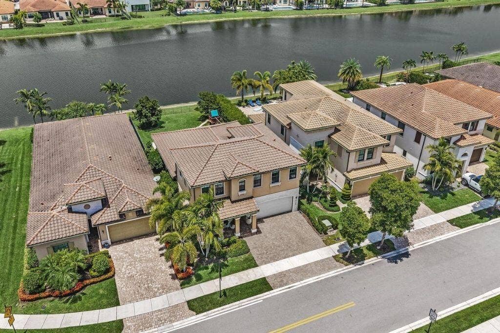 12143 S Baypoint Circle, Parkland, FL 33076 Tile-roofed residence featuring a paved driveway, a two-car garage, and mature landscaping