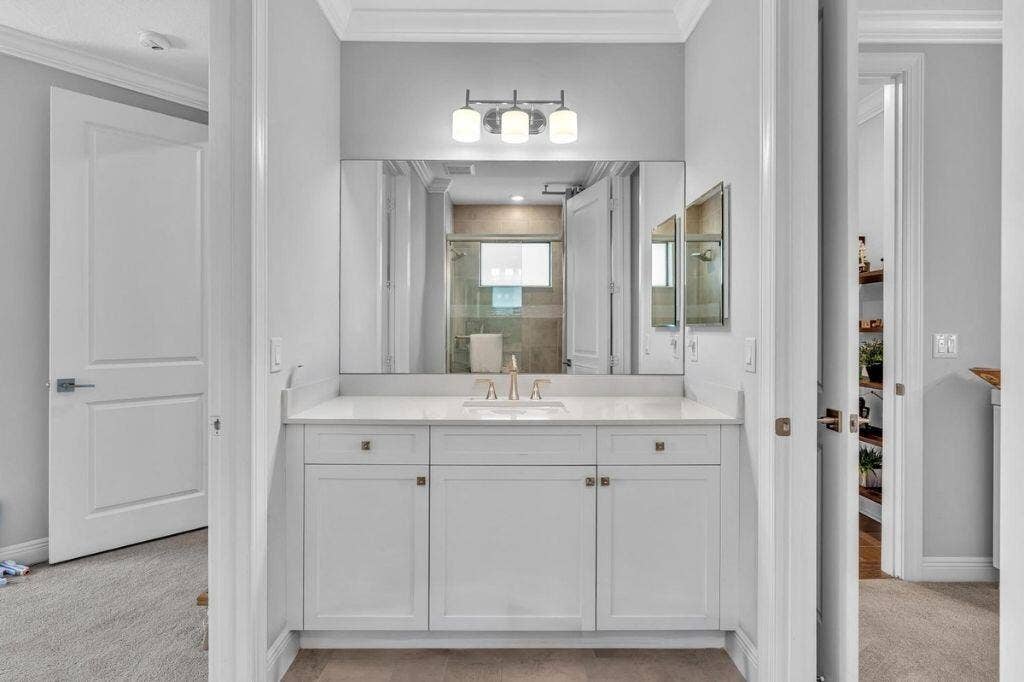 12143 S Baypoint Circle, Parkland, FL 33076 Bathroom vanity featuring white cabinetry, a light-toned countertop, and an integrated rectangular sink with a gold-tone faucet