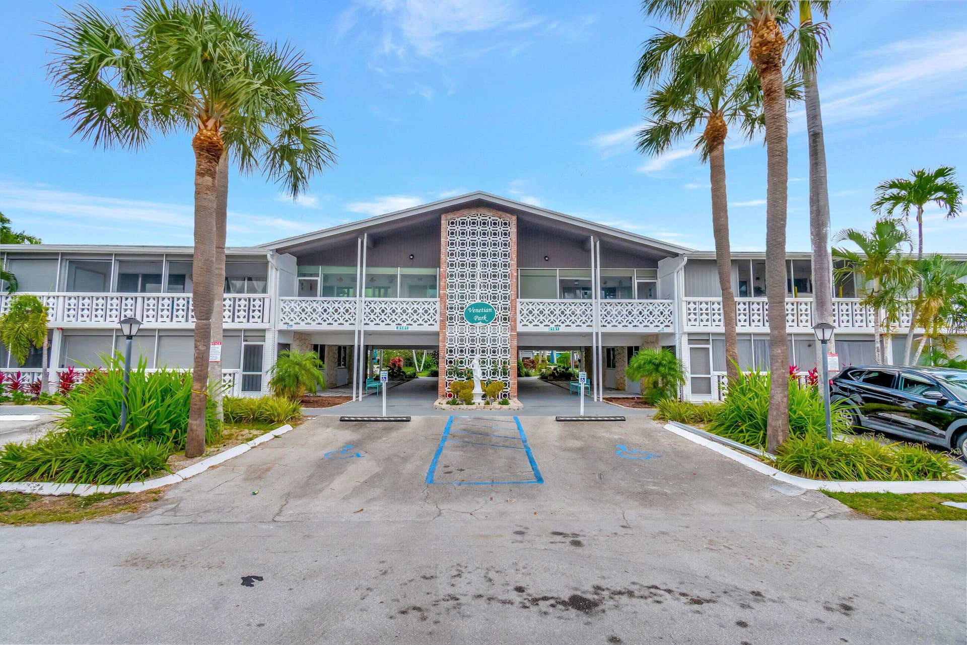 2161 NE 42nd Court, #116, Lighthouse Point, FL 33064 Two-story residential building with screened lanais, decorative white balcony railings, and a central breezeway entrance