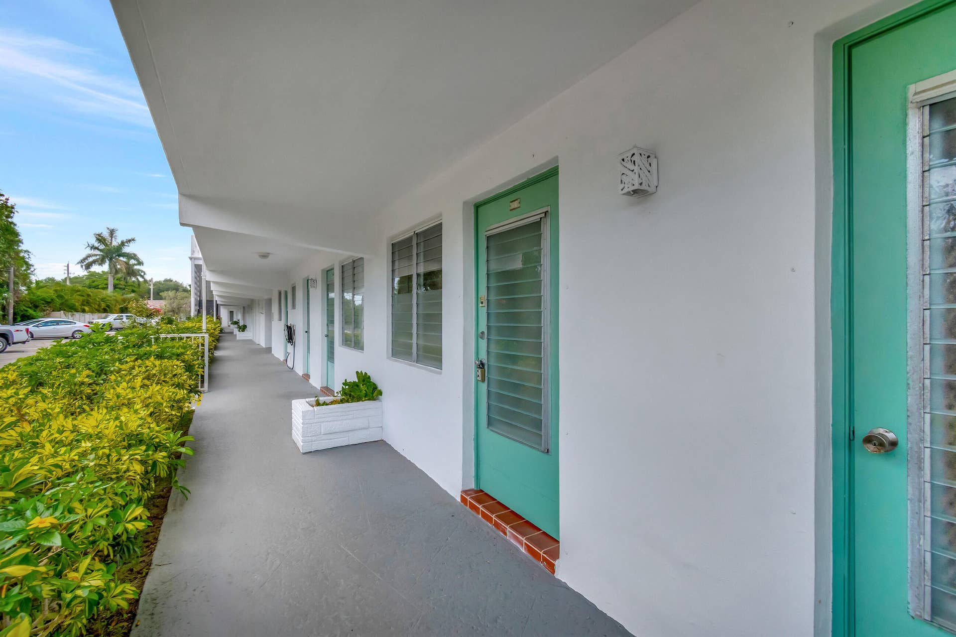 2161 NE 42nd Court, #116, Lighthouse Point, FL 33064 Covered walkway with an overhead soffit, exterior wall lighting, and vibrant green entry doors