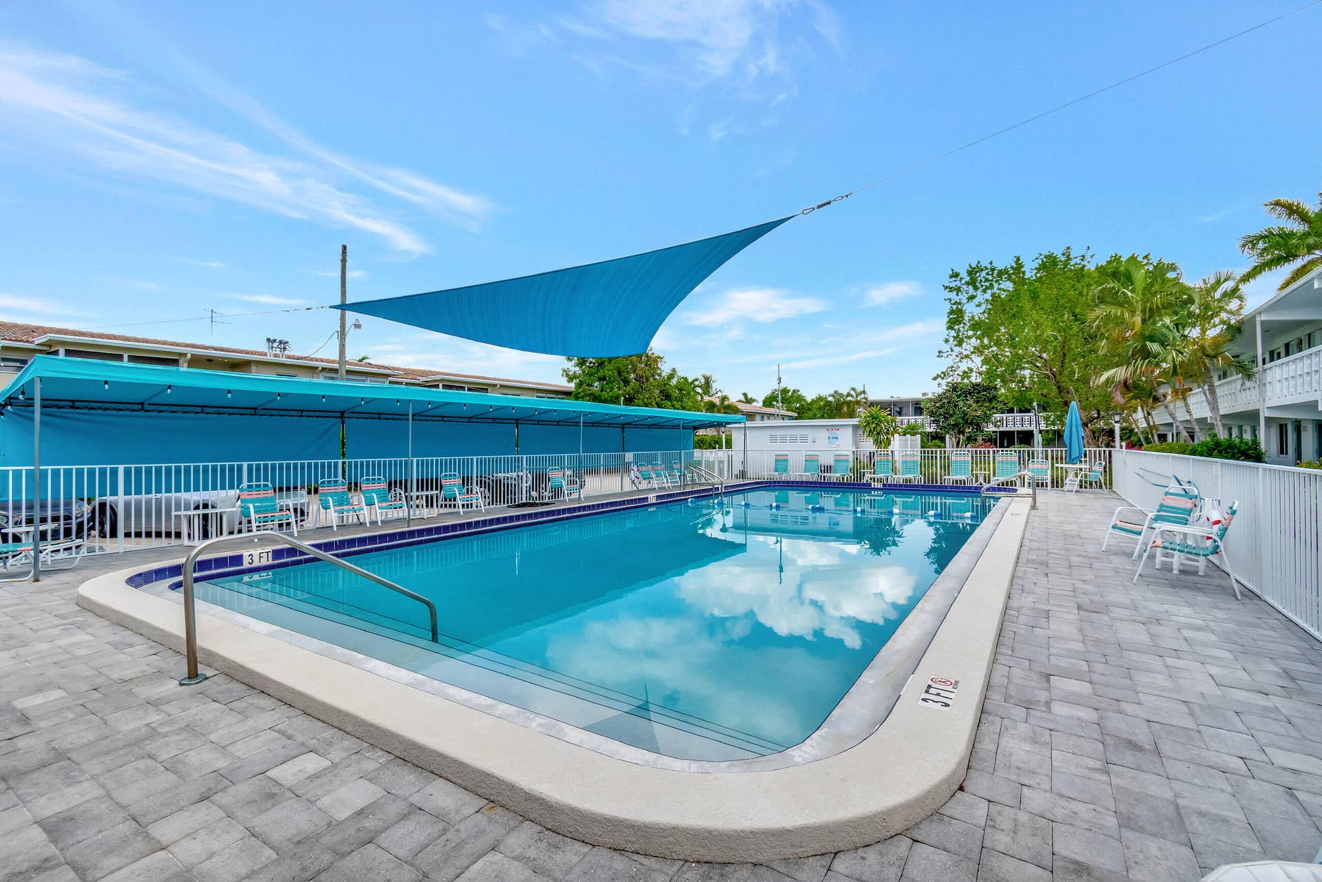 2161 NE 42nd Court, #116, Lighthouse Point, FL 33064 Resort-style swimming pool with integrated steps, surrounded by a paver patio and a white perimeter fence