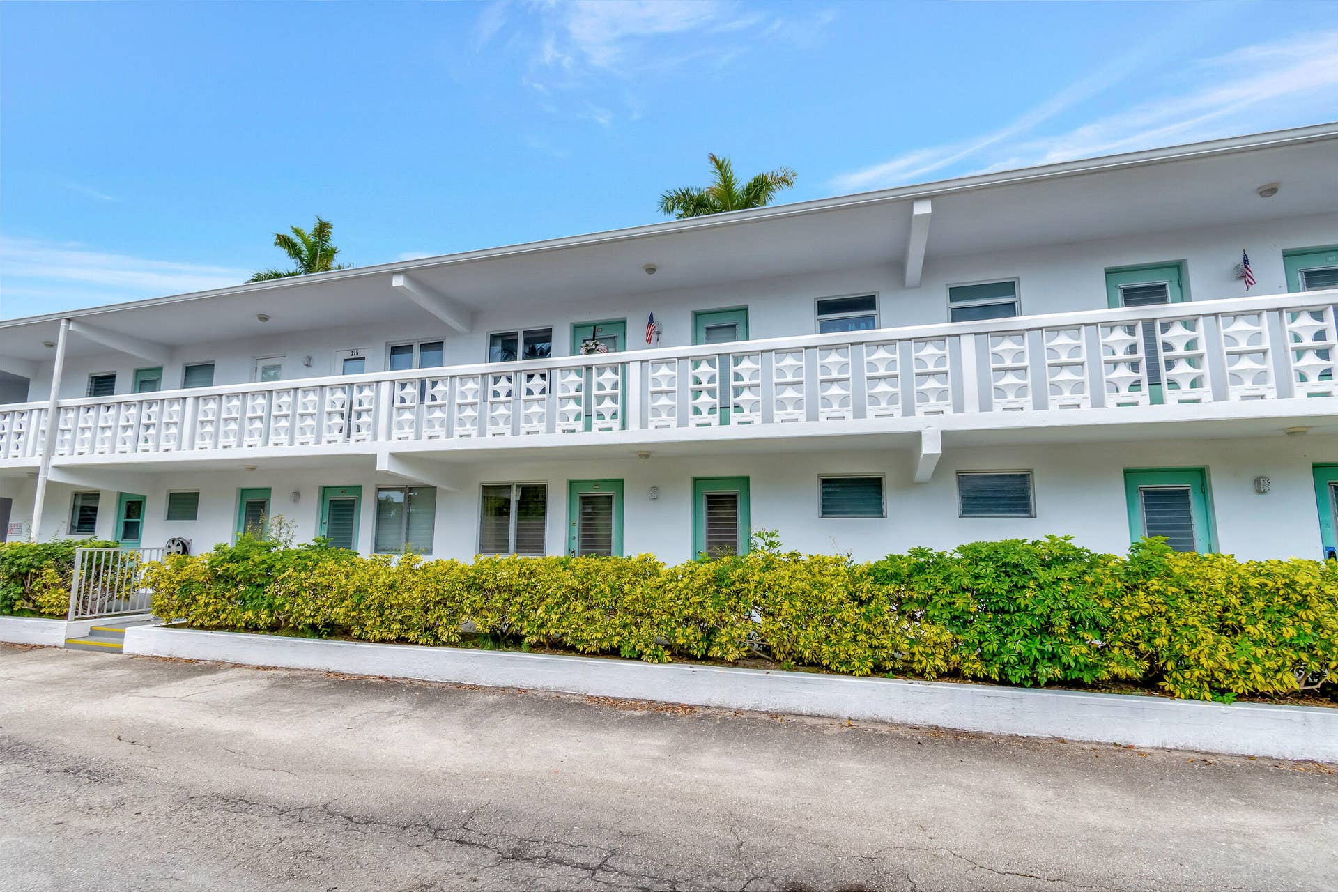 2161 NE 42nd Court, #116, Lighthouse Point, FL 33064 Two-story stucco exterior with a repeating geometric pattern balcony railing and mature landscaping