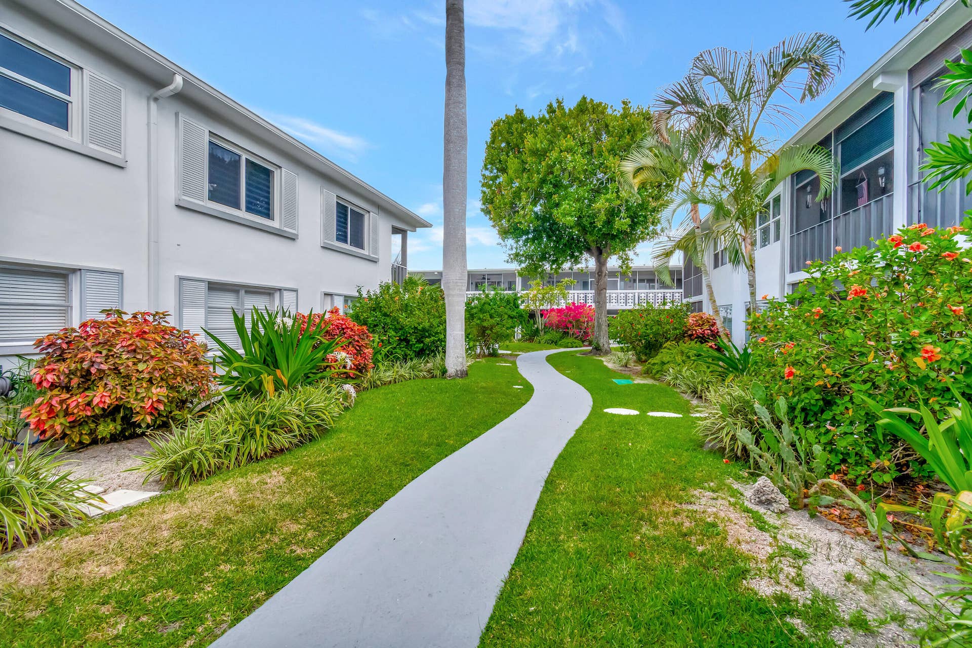2161 NE 42nd Court, #116, Lighthouse Point, FL 33064 Lush landscaping with mature trees, established shrubs, and flowering plants