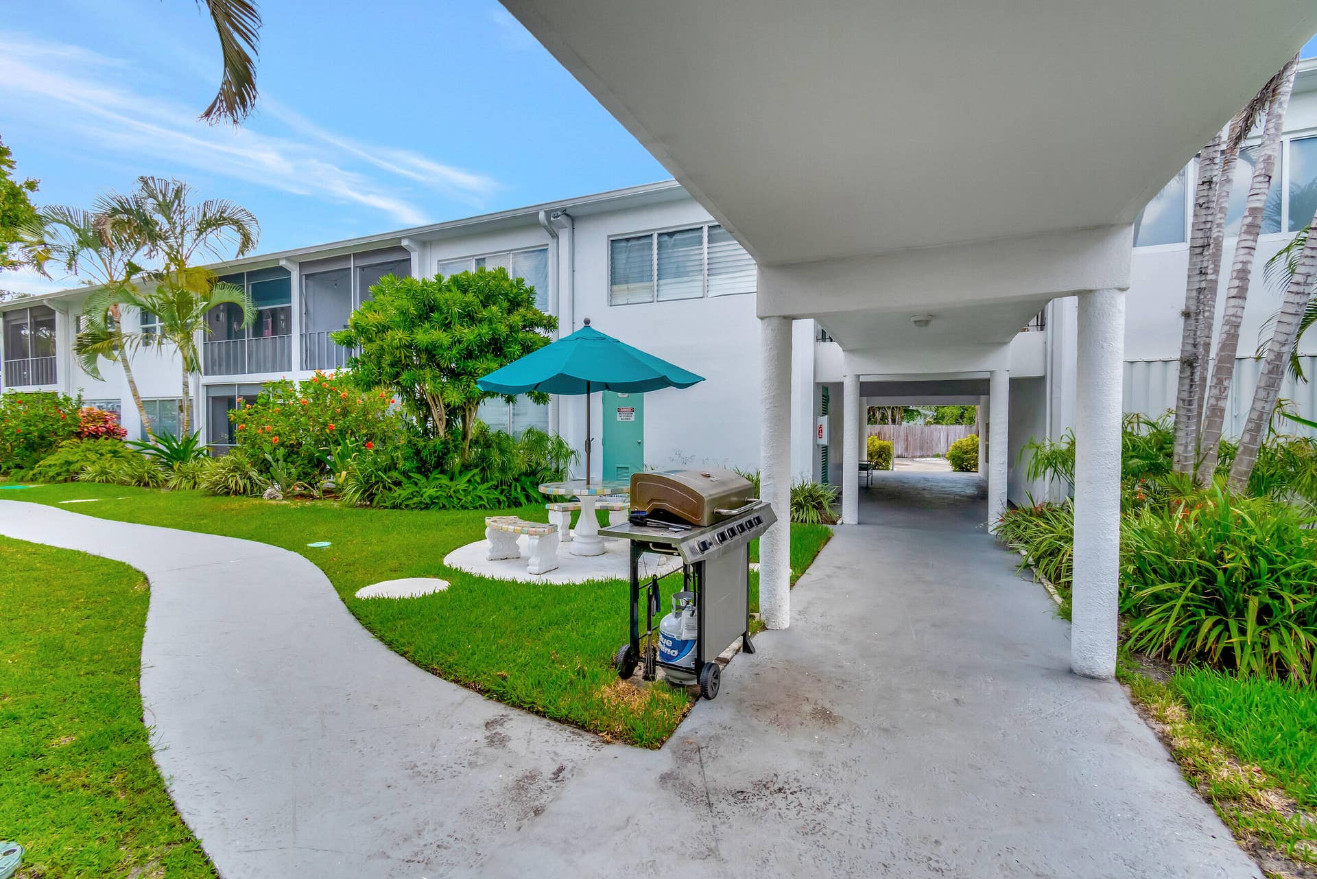 2161 NE 42nd Court, #116, Lighthouse Point, FL 33064 Exterior features include a white stucco facade, screened balconies, and a concrete walkway