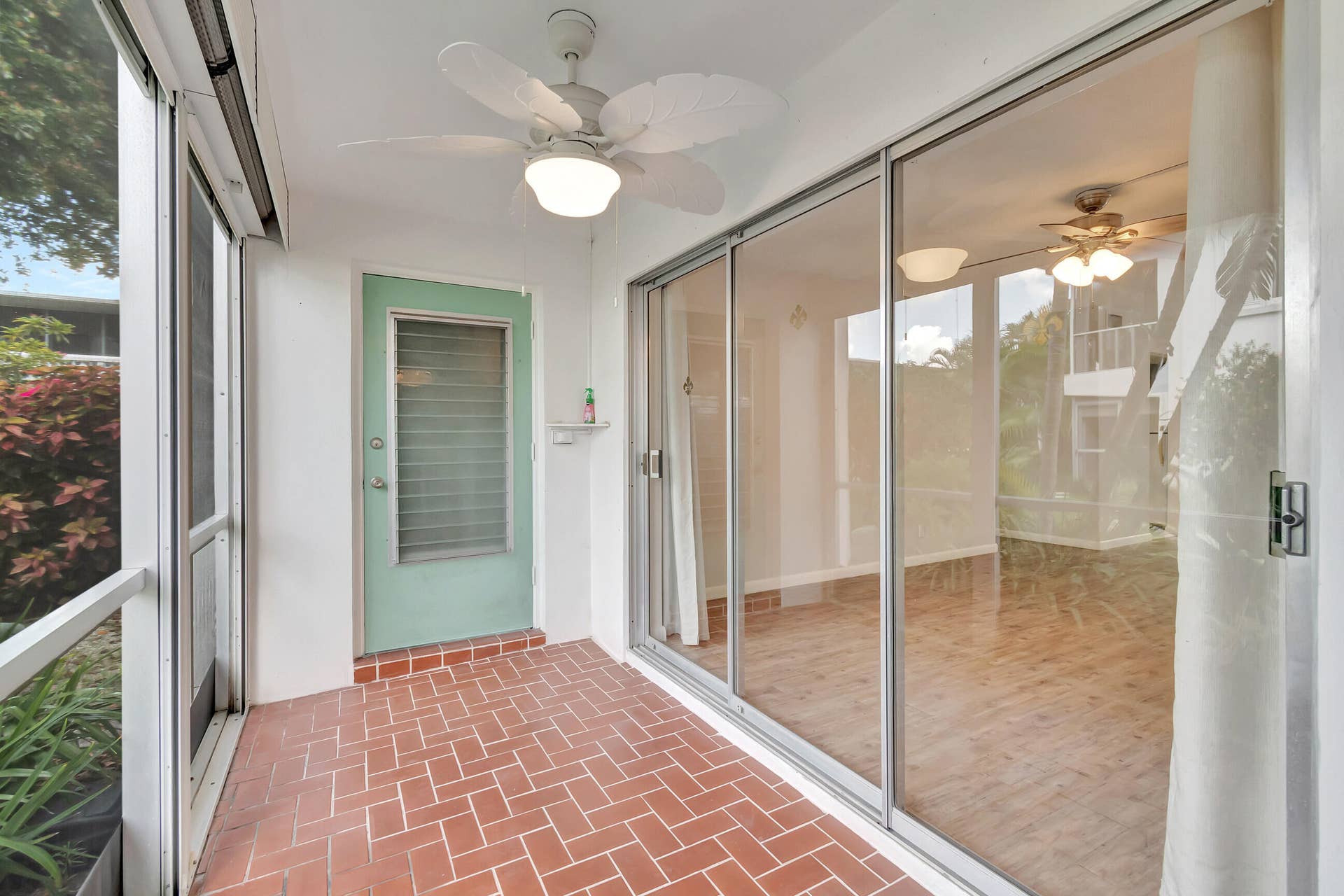 2161 NE 42nd Court, #116, Lighthouse Point, FL 33064 Screened porch featuring a ceiling fan with light, brick-patterned flooring, and sliding glass doors