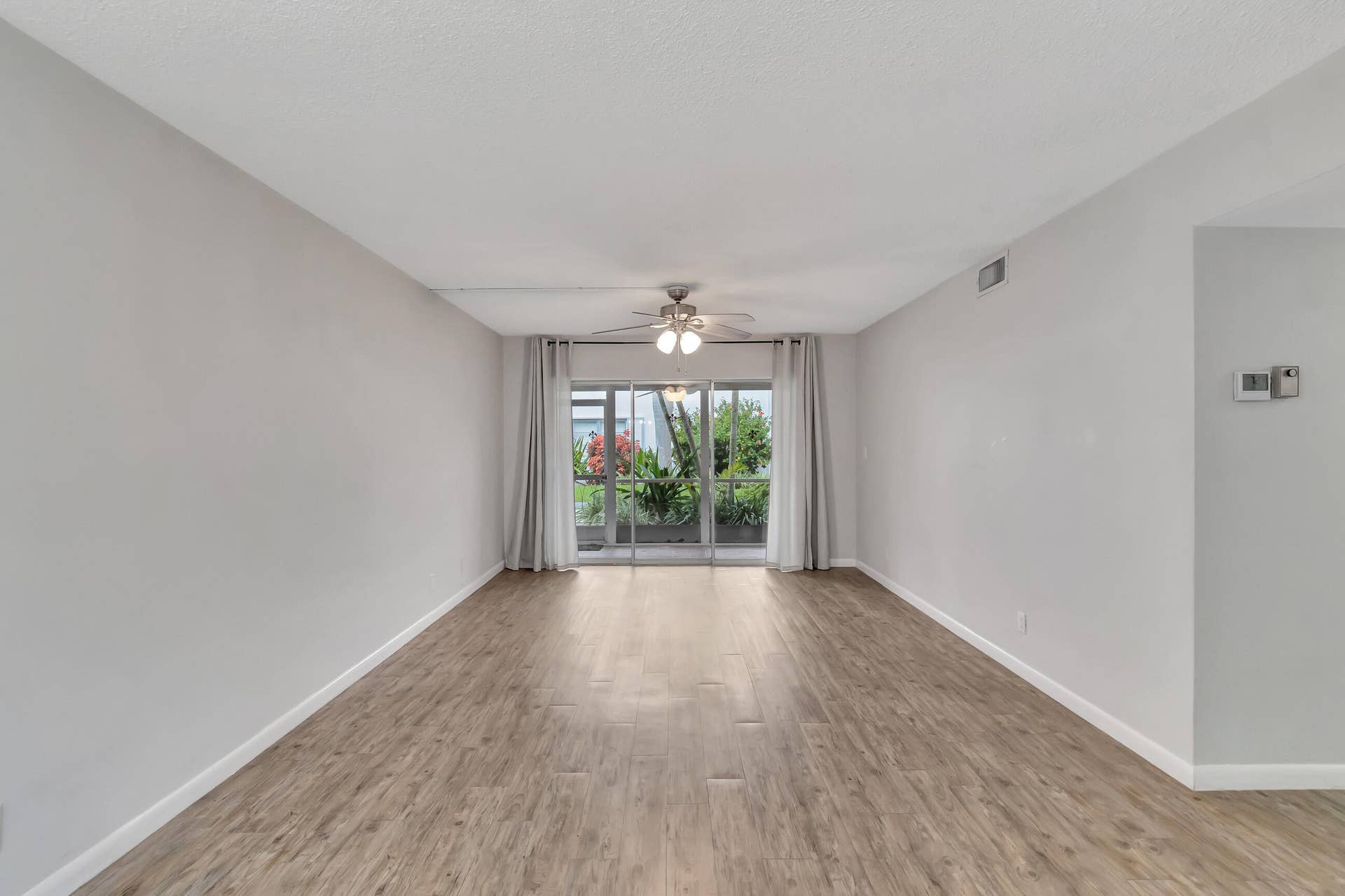 2161 NE 42nd Court, #116, Lighthouse Point, FL 33064 Expansive room featuring wood-finish flooring, light gray walls, and a ceiling fan