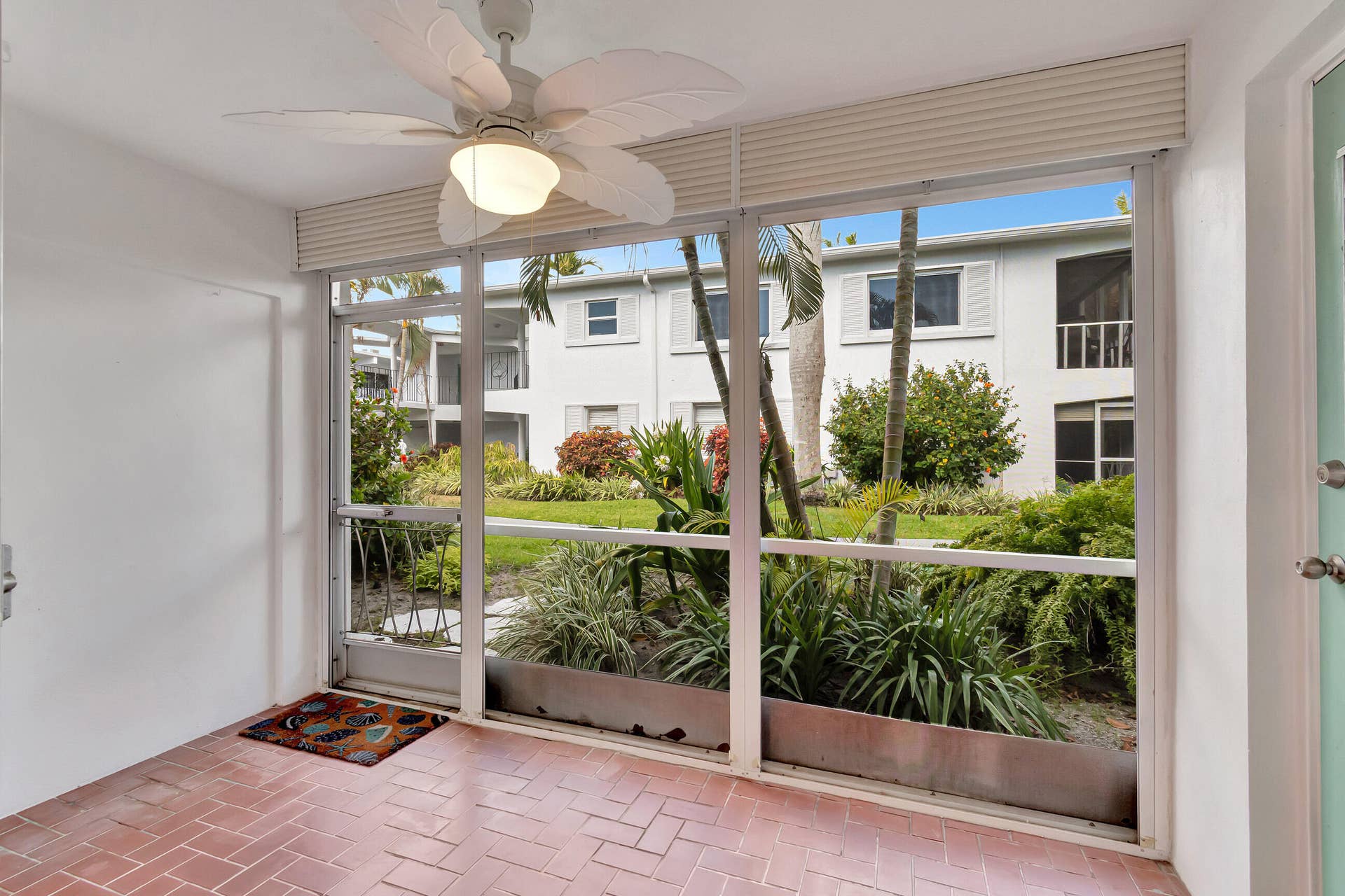 2161 NE 42nd Court, #116, Lighthouse Point, FL 33064 Screened enclosure with terracotta tile flooring, ceiling fan with integrated lighting, and white panel walls