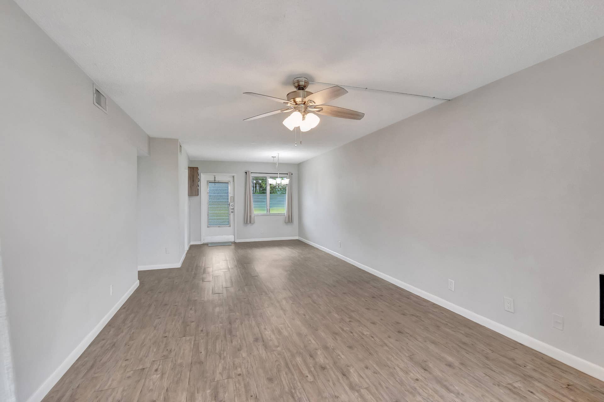 2161 NE 42nd Court, #116, Lighthouse Point, FL 33064 Light-toned wood-finish flooring, ceiling fan with integrated lighting, white walls, and a glass-paneled exterior door