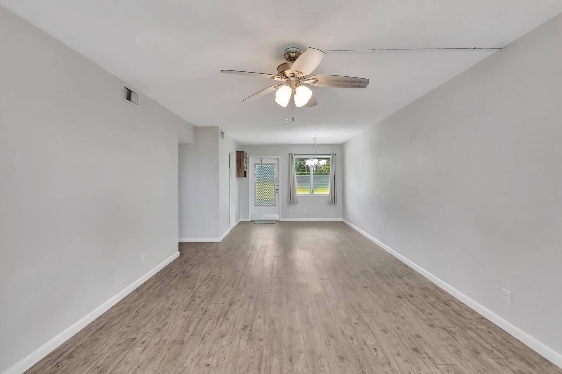 2161 NE 42nd Court, #116, Lighthouse Point, FL 33064 Expansive interior with wood-finish flooring, light gray walls, a ceiling fan, and a glass-paneled exterior door