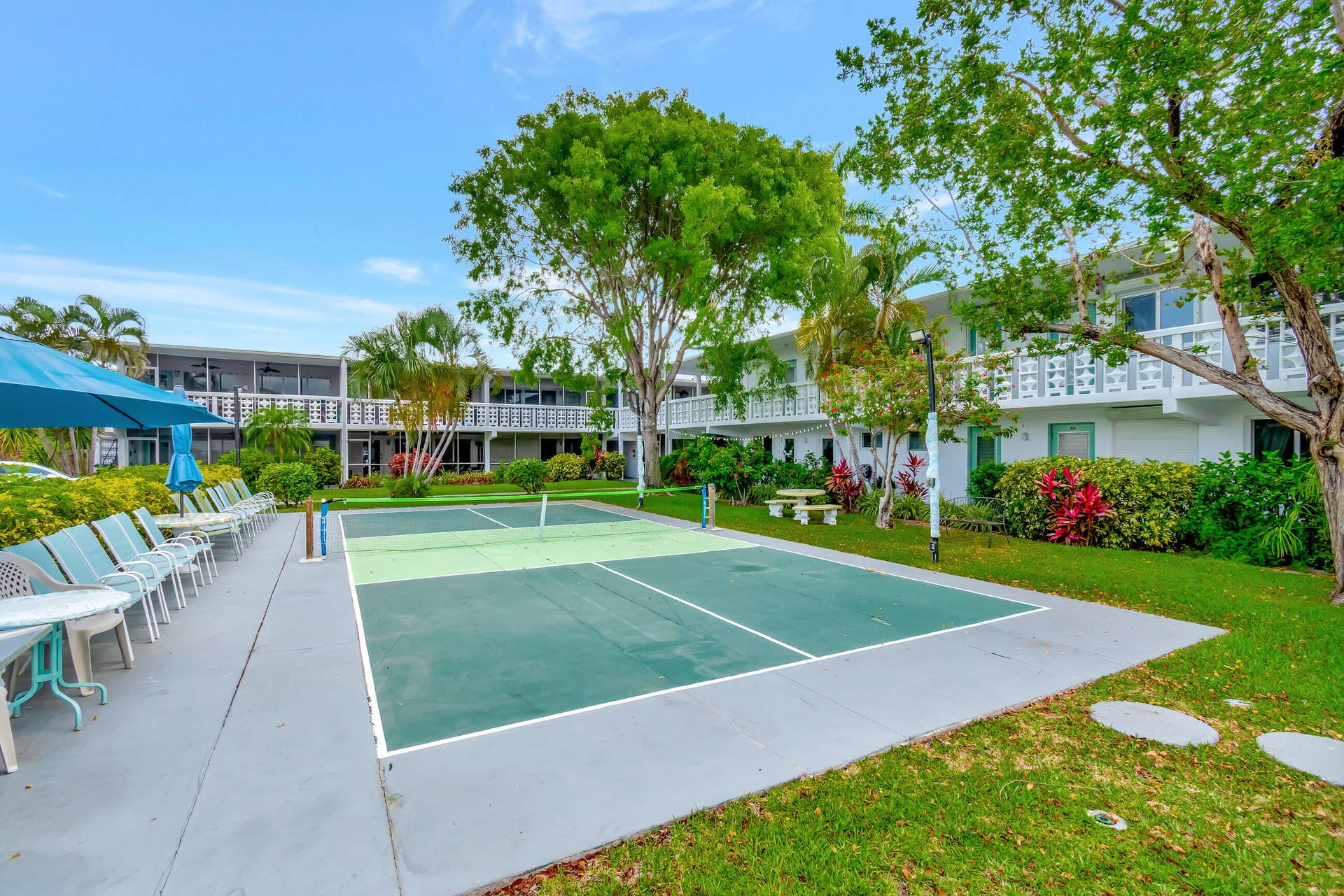 2161 NE 42nd Court, #116, Lighthouse Point, FL 33064 Outdoor court for recreation, extensive hardscaping, mature trees, manicured lawns, and multi-story white buildings with balconies