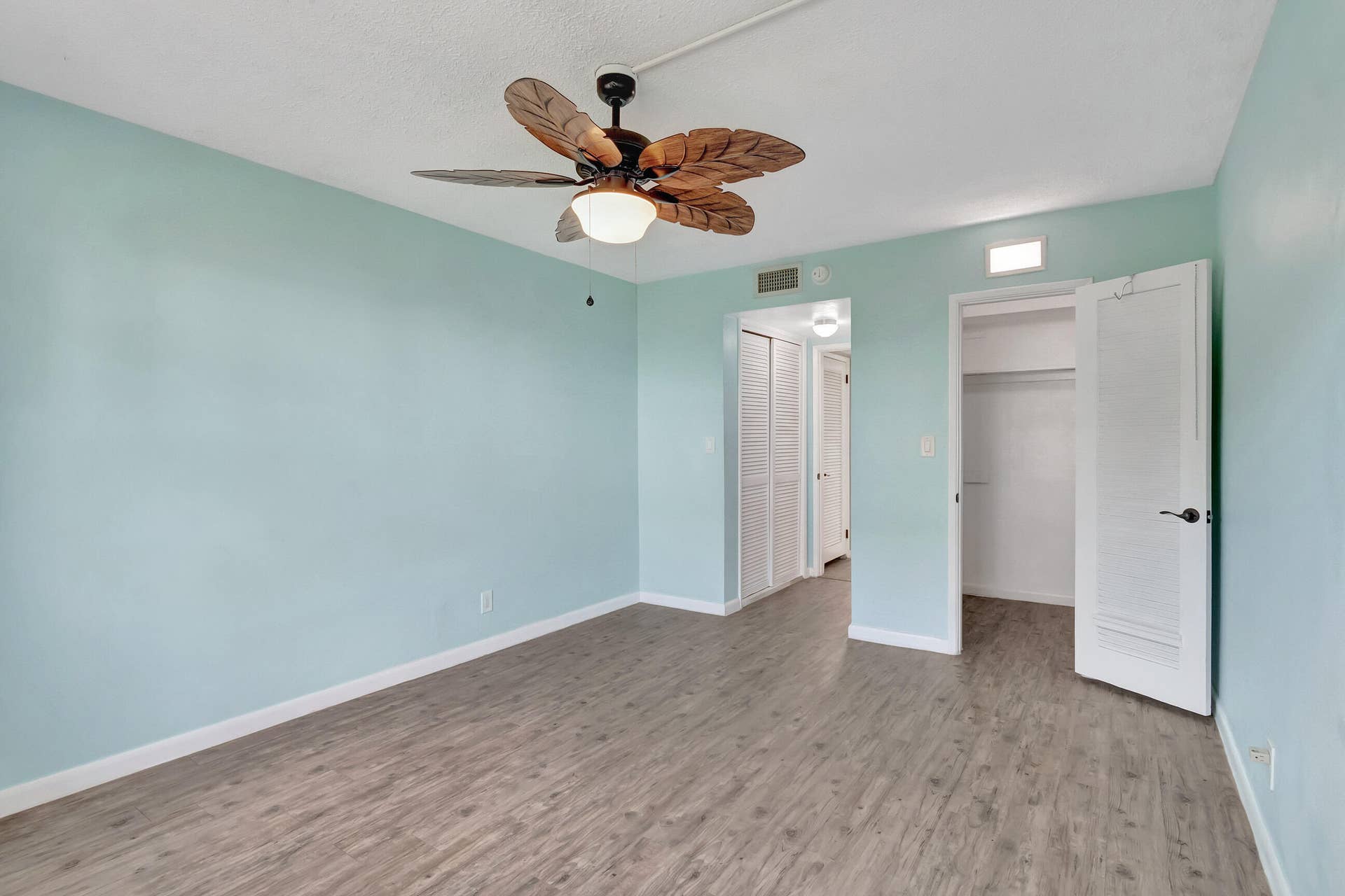 2161 NE 42nd Court, #116, Lighthouse Point, FL 33064 Room featuring wood-finish flooring, a ceiling fan with integrated lighting, and a closet with louvered bifold doors