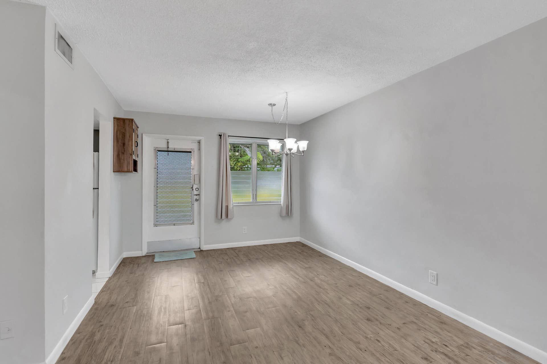 2161 NE 42nd Court, #116, Lighthouse Point, FL 33064 Wood-finish flooring, light gray walls, built-in wooden cabinet, and window with exterior landscaping
