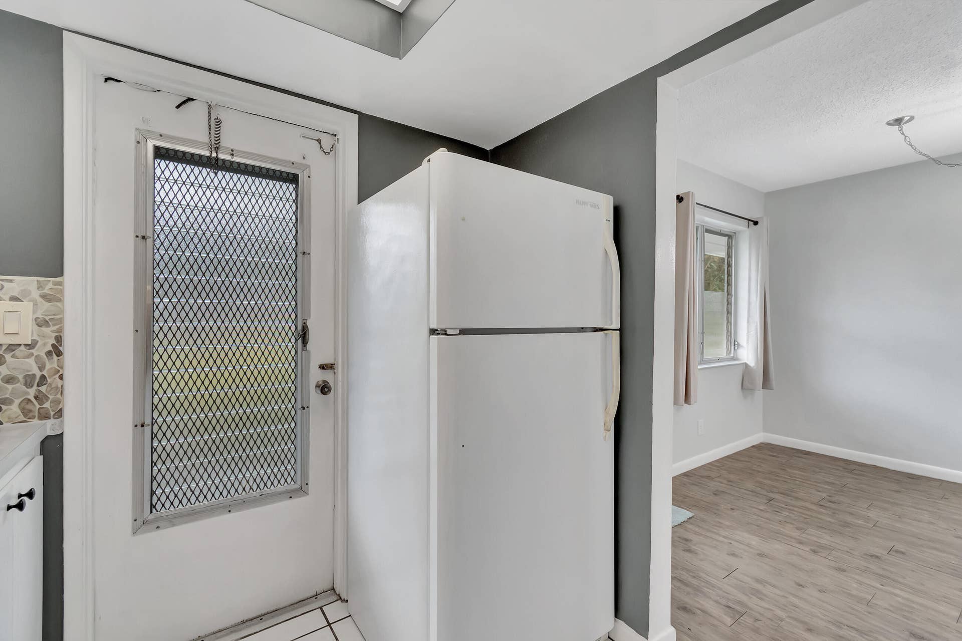 2161 NE 42nd Court, #116, Lighthouse Point, FL 33064 Kitchen featuring a mosaic tile backsplash, white cabinetry with dark hardware, and an attached refrigerator
