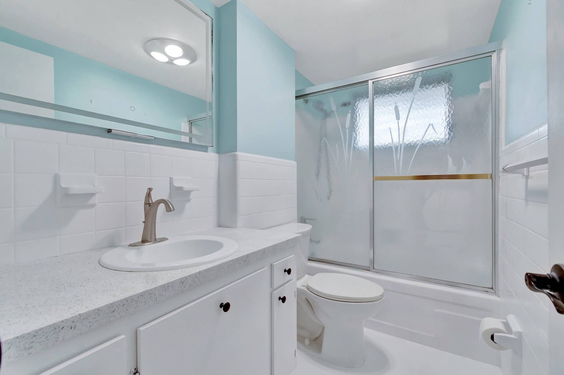 2161 NE 42nd Court, #116, Lighthouse Point, FL 33064 Bathroom featuring a white vanity with integrated sink, brushed nickel faucet, and a sliding glass shower enclosure with frosted accents