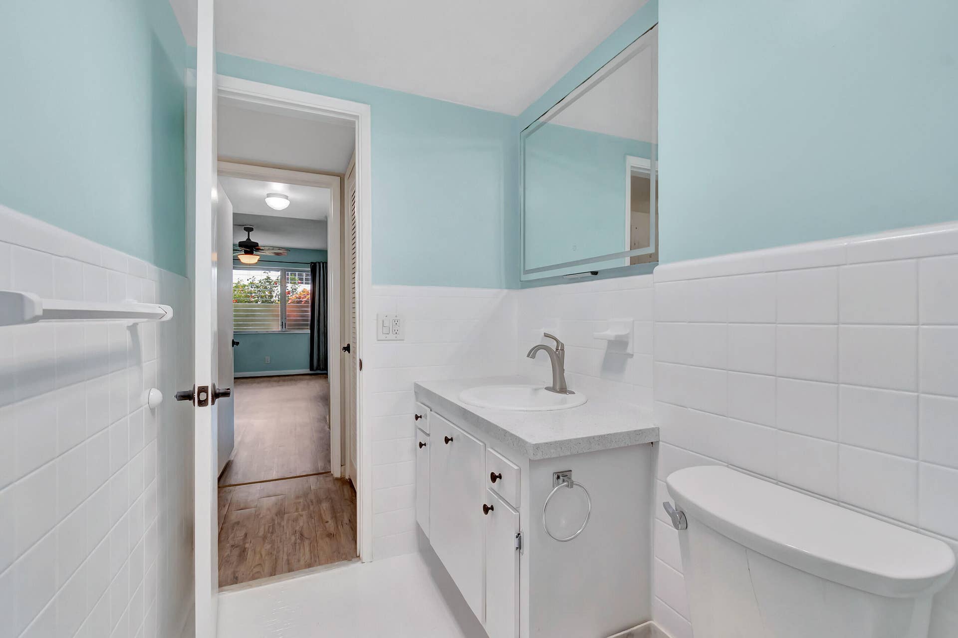 2161 NE 42nd Court, #116, Lighthouse Point, FL 33064 Bathroom featuring a single vanity with a white countertop, an integrated sink, a medicine cabinet, and white tile wainscoting