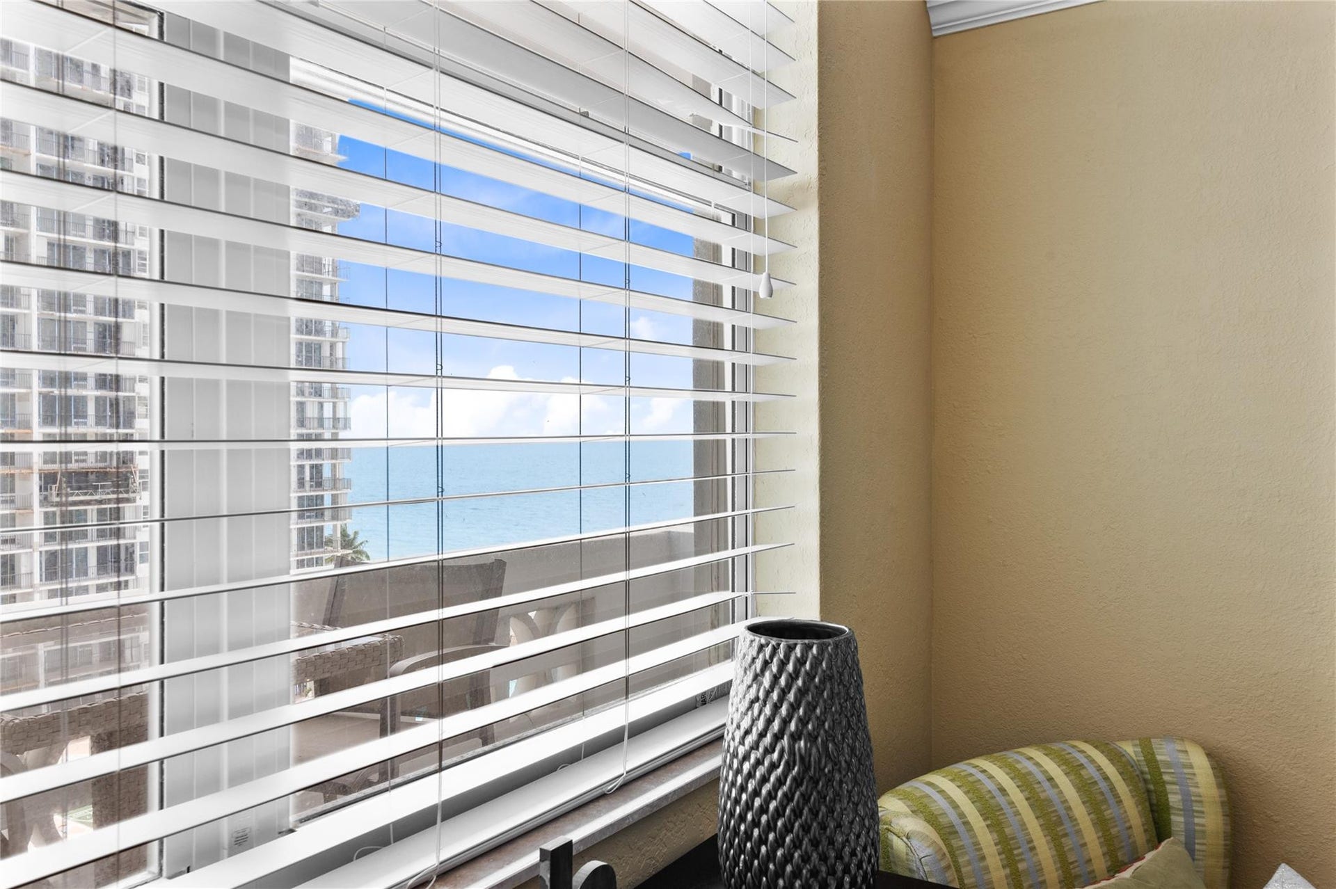 4250 GALT OCEAN Drive, #8L, Fort Lauderdale, Fort Lauderdale, FL 33308 Expansive window with horizontal blinds, offering a glimpse of the ocean and adjacent high-rise buildings