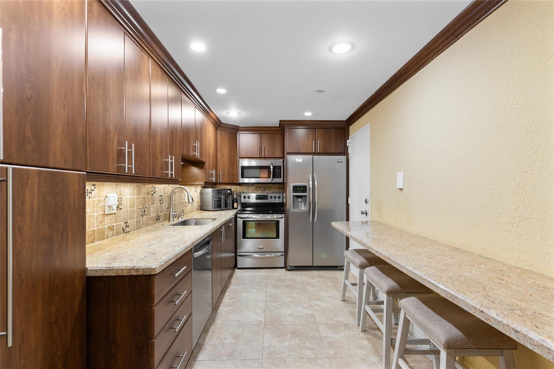 4250 GALT OCEAN Drive, #8L, Fort Lauderdale, Fort Lauderdale, FL 33308 Galley kitchen featuring wood cabinetry, stainless steel appliances, recessed lighting, tile flooring, and light-toned countertops