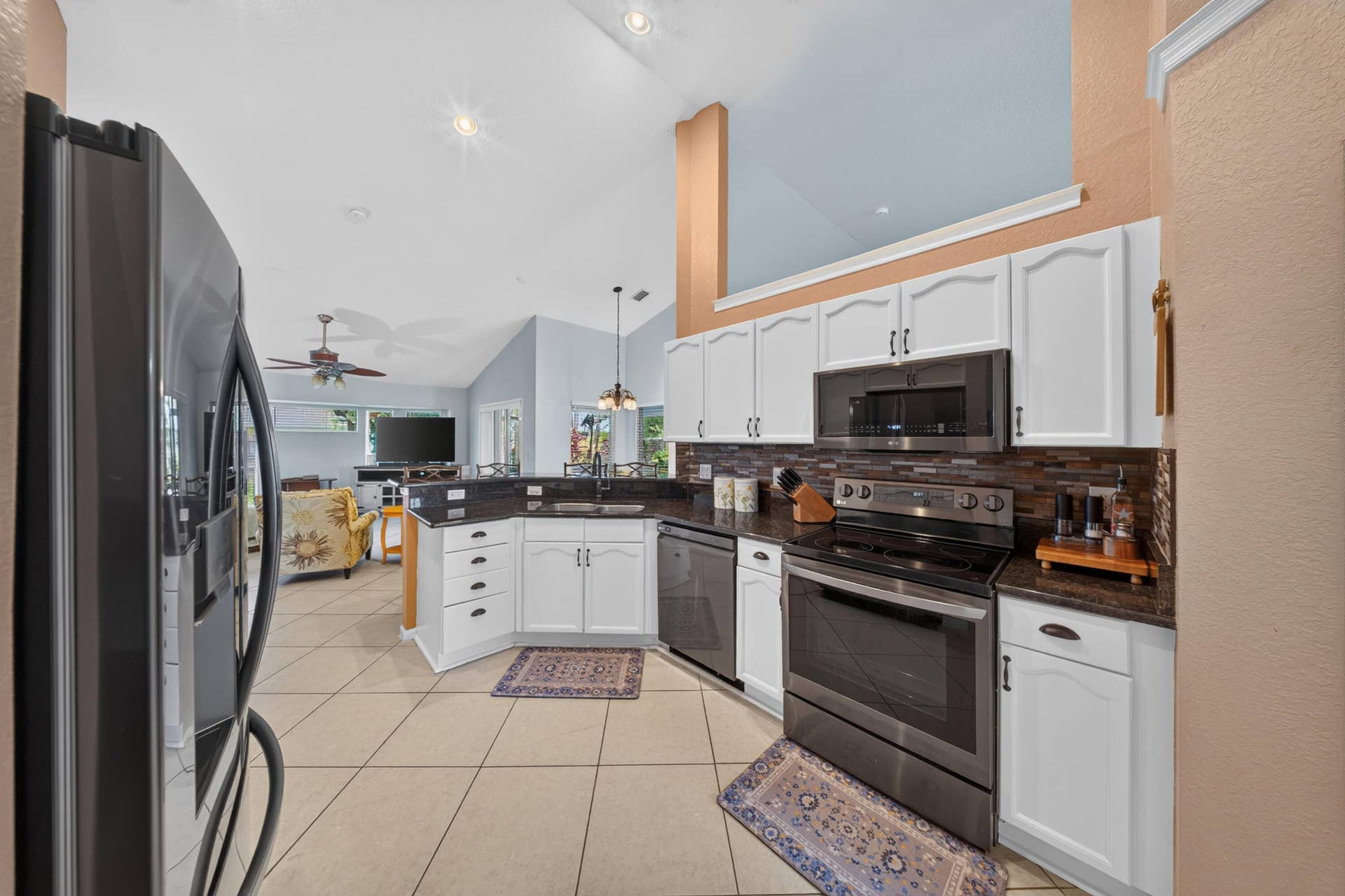 3274 SW CRUMPACKER Street, Port St Lucie, FL 34953 Kitchen featuring white cabinetry, dark countertops, dark tile backsplash, stainless steel appliances, and tile flooring