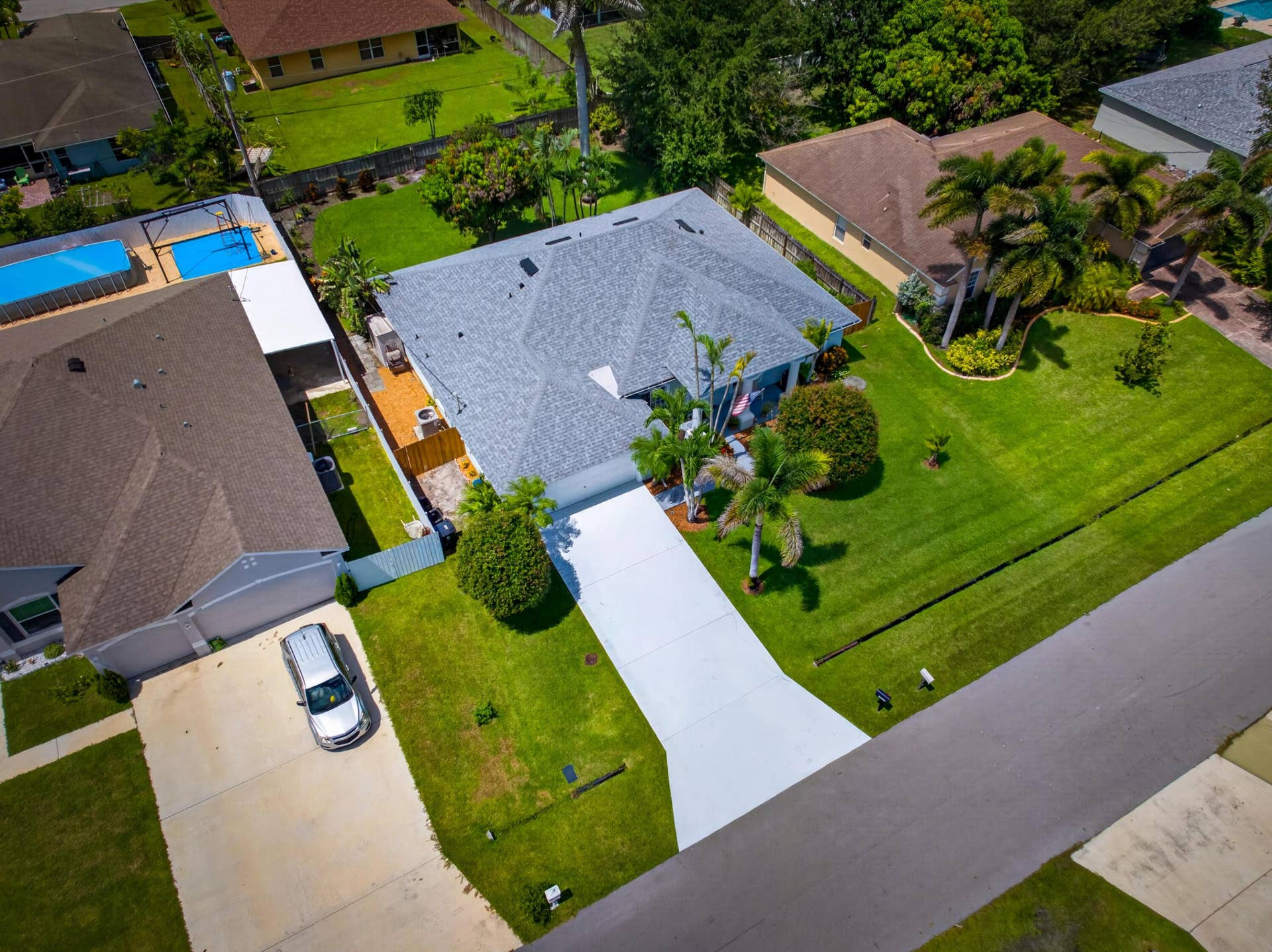 3274 SW CRUMPACKER Street, Port St Lucie, FL 34953 Single-story residence featuring a shingle roof, expansive front lawn with mature landscaping, and a concrete driveway